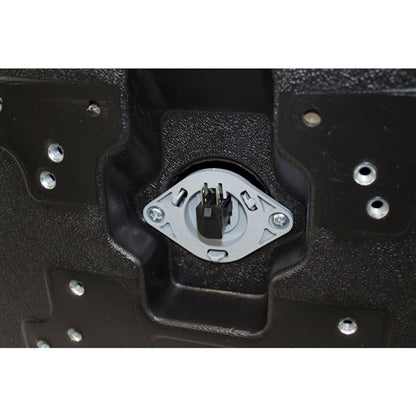 Underside of a black plastic tractor seat with a central safety switch and multiple mounting hole patterns.